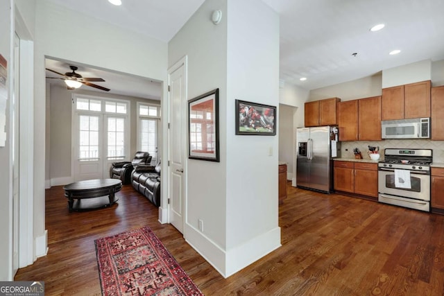 kitchen featuring dark wood-style flooring, brown cabinets, stainless steel appliances, tasteful backsplash, and light countertops