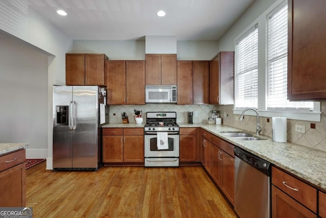 kitchen with light stone countertops, stainless steel appliances, a sink, and wood finished floors