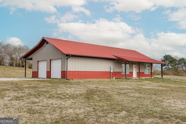 view of front of home featuring an outbuilding, metal roof, a detached garage, and a front yard