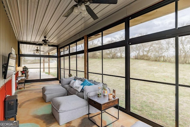 sunroom / solarium featuring a wood stove and a ceiling fan