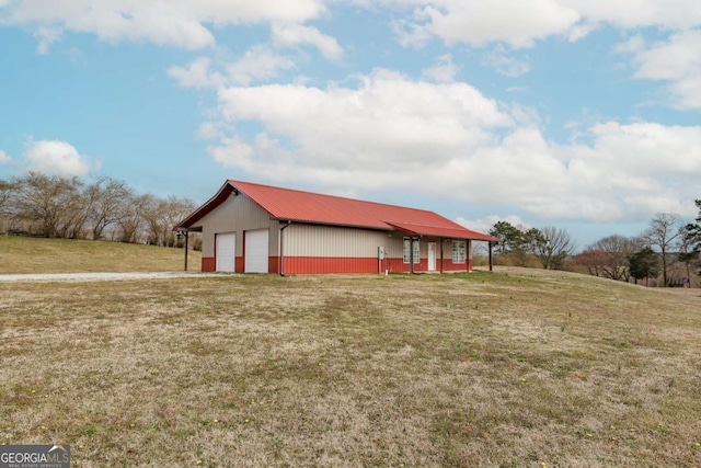 view of side of property featuring an outbuilding, metal roof, and a yard