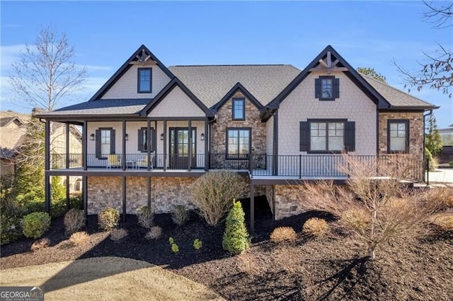 view of front of house with stone siding and roof with shingles