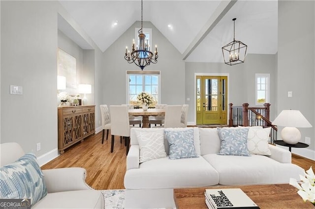 living room with a chandelier, high vaulted ceiling, baseboards, and wood finished floors