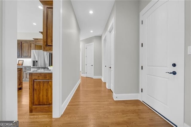 hallway with baseboards, recessed lighting, and light wood-style floors