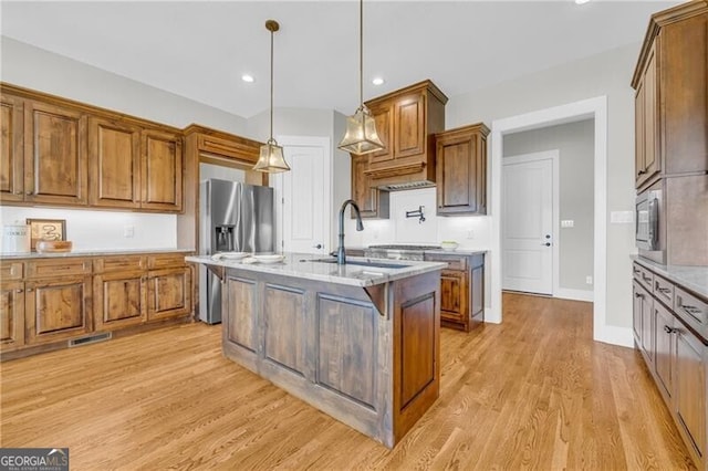 kitchen featuring light wood-type flooring, brown cabinetry, and a sink