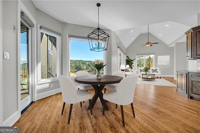 dining room featuring lofted ceiling, a chandelier, light wood-style flooring, and baseboards