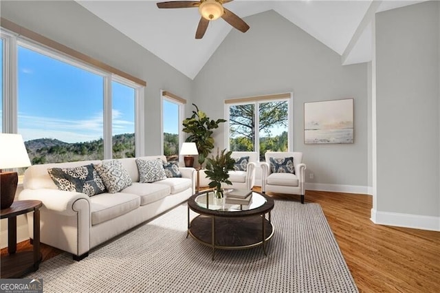 living room featuring high vaulted ceiling, a ceiling fan, baseboards, and wood finished floors