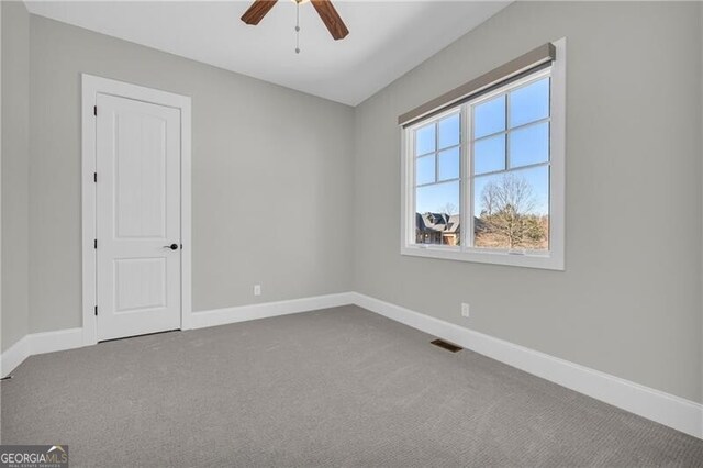 spare room with carpet, visible vents, ceiling fan, and baseboards