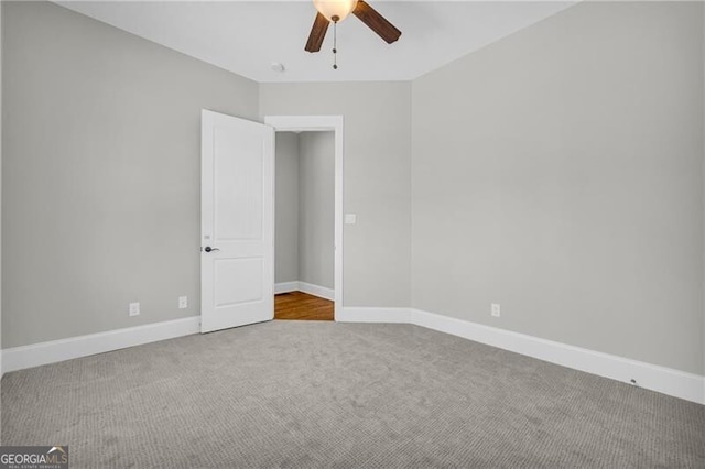 spare room featuring carpet floors, ceiling fan, and baseboards