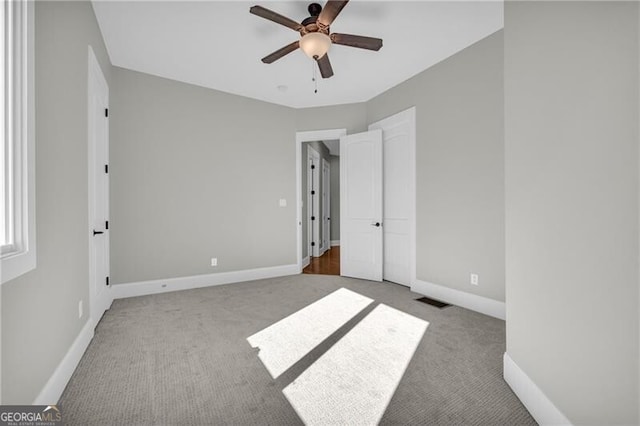 unfurnished bedroom featuring ceiling fan, carpet flooring, visible vents, and baseboards