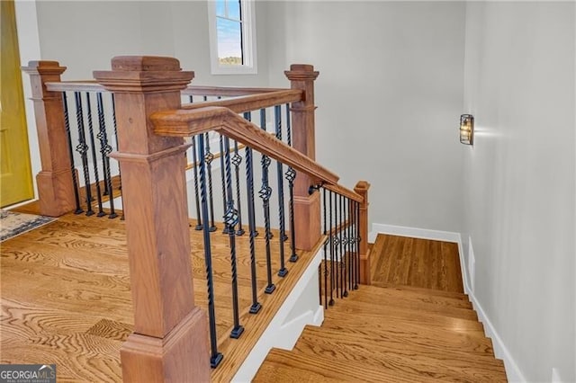 staircase featuring wood finished floors and baseboards