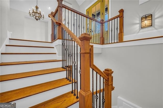 stairs featuring a chandelier