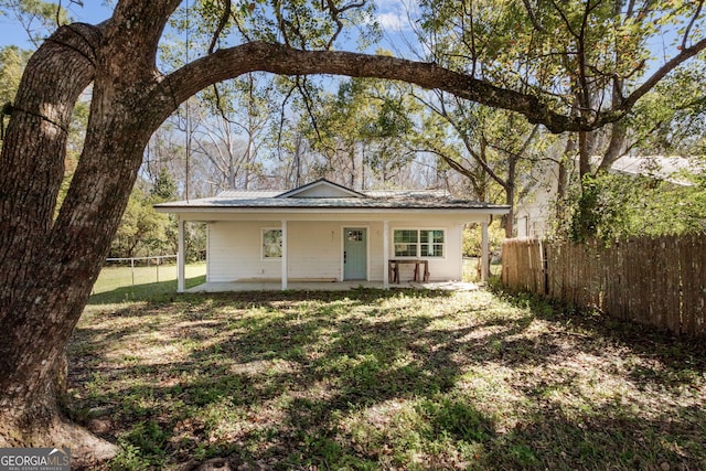 view of front of house with metal roof, fence, and a front lawn