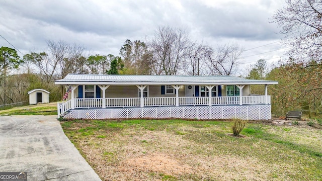 view of front of house featuring a porch, metal roof, and a front lawn