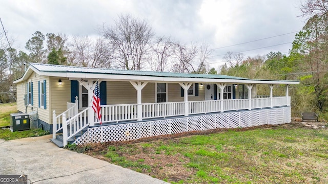 view of front of home with a porch, central air condition unit, a front lawn, and metal roof