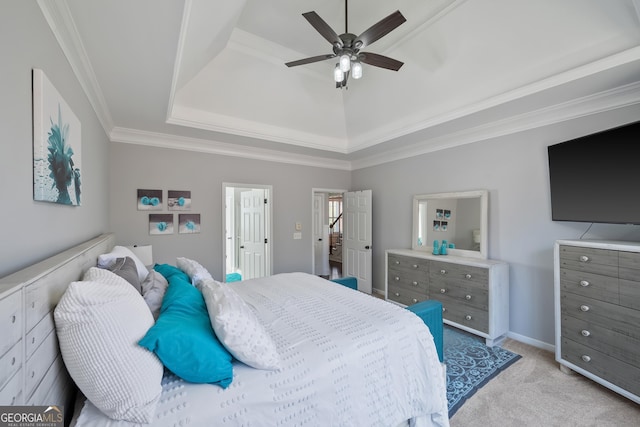 bedroom with baseboards, light colored carpet, a tray ceiling, ornamental molding, and a ceiling fan