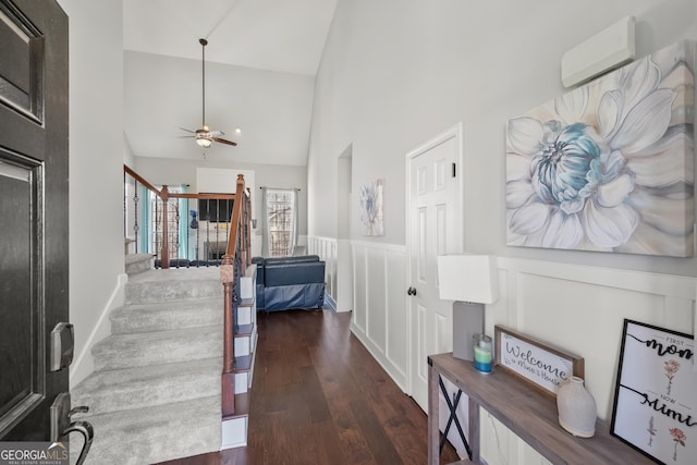 hall featuring a wall mounted air conditioner, high vaulted ceiling, wood finished floors, stairway, and wainscoting