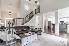 living area with ceiling fan, a towering ceiling, and decorative columns