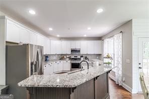 kitchen featuring a spacious island, light stone counters, a kitchen breakfast bar, appliances with stainless steel finishes, and white cabinets