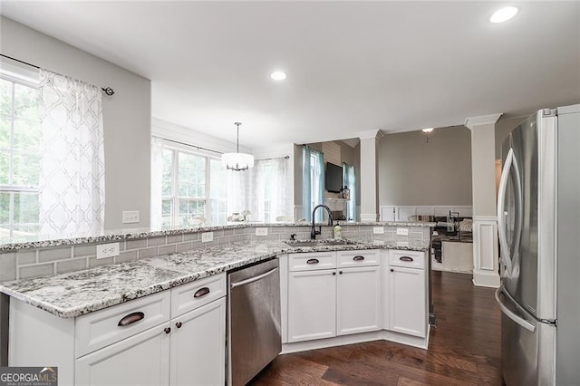 kitchen with light stone counters, white cabinetry, stainless steel appliances, and a sink