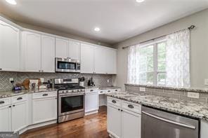 kitchen featuring white cabinetry, dark wood finished floors, tasteful backsplash, and stainless steel appliances