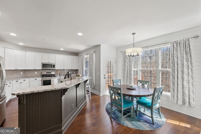 kitchen featuring light stone counters, dark wood-style floors, tasteful backsplash, and appliances with stainless steel finishes