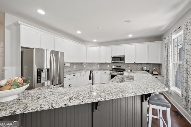 kitchen featuring light stone counters, stainless steel appliances, a breakfast bar, and decorative backsplash