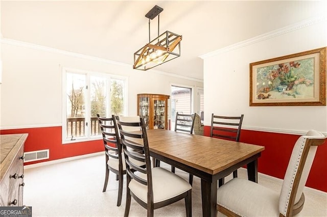 dining room featuring carpet floors, visible vents, crown molding, and baseboards