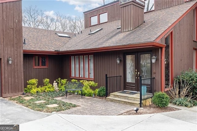 property entrance featuring french doors and roof with shingles