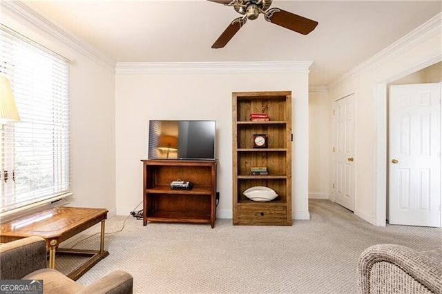 living area with light carpet, ceiling fan, baseboards, and crown molding