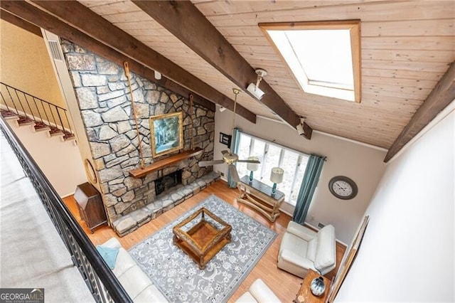 unfurnished living room featuring vaulted ceiling with skylight, wood ceiling, a stone fireplace, and wood finished floors