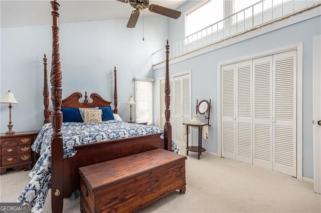 carpeted bedroom featuring baseboards, a high ceiling, a ceiling fan, and multiple closets