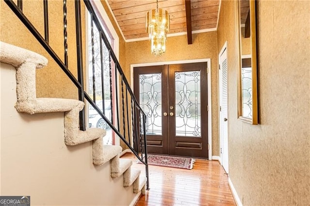 entryway featuring a chandelier, hardwood / wood-style flooring, wood ceiling, stairway, and beam ceiling