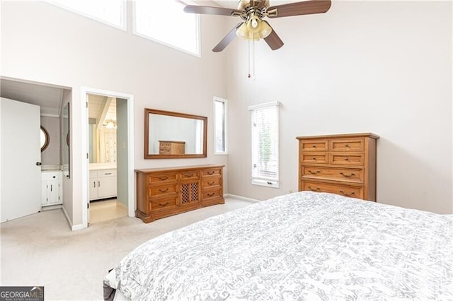 bedroom with a ceiling fan, light carpet, a towering ceiling, and multiple windows