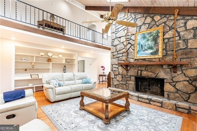 living area featuring a fireplace, a high ceiling, wood finished floors, and beamed ceiling