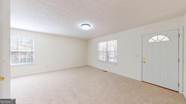 carpeted entrance foyer with a textured ceiling and baseboards