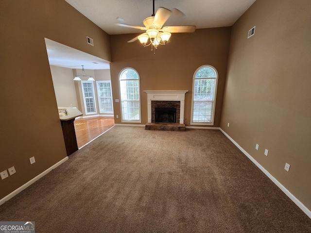 unfurnished living room featuring carpet, visible vents, a stone fireplace, and baseboards