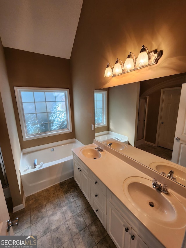 full bathroom with vaulted ceiling, a sink, and a bath