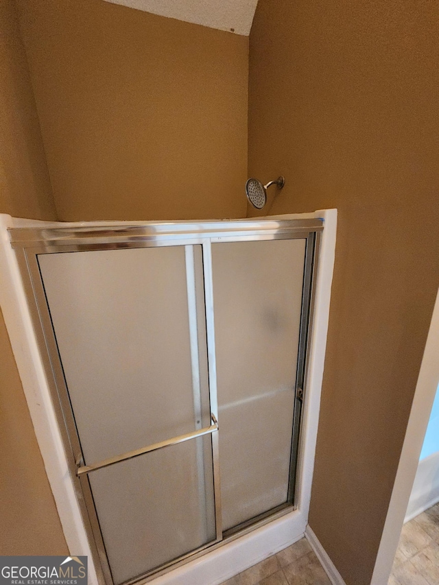 full bathroom featuring a shower with shower door and baseboards