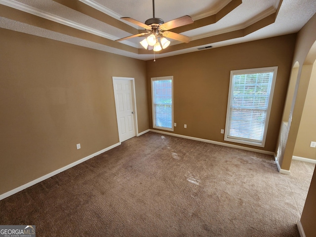 unfurnished bedroom with baseboards, visible vents, a raised ceiling, and crown molding