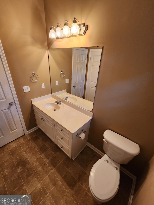 bathroom with toilet, baseboards, and vanity