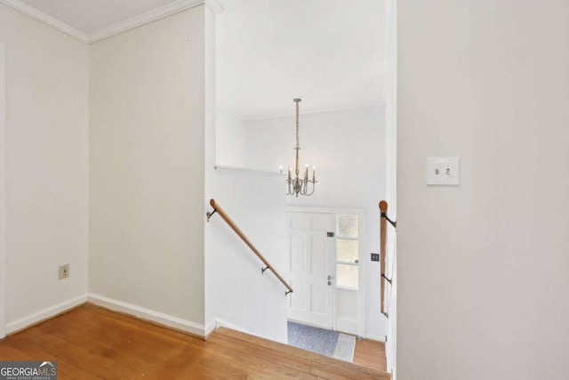 entryway with a chandelier, ornamental molding, baseboards, and wood finished floors