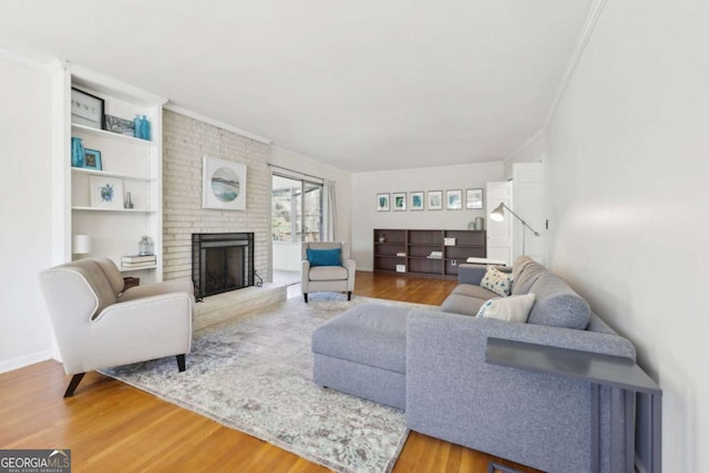 living room featuring ornamental molding, a brick fireplace, and wood finished floors