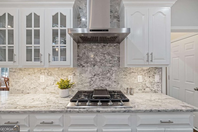 kitchen featuring glass insert cabinets, white cabinetry, stainless steel gas cooktop, and wall chimney exhaust hood