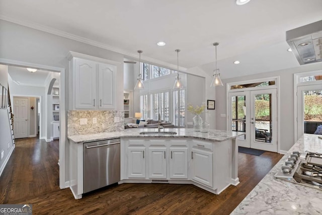 kitchen featuring tasteful backsplash, a peninsula, stainless steel appliances, white cabinetry, and a sink