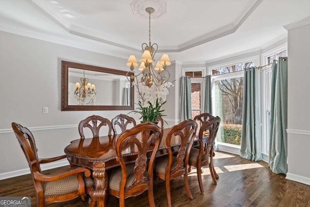 dining space with crown molding, a tray ceiling, dark wood-style flooring, and a notable chandelier