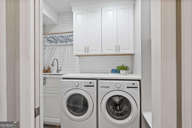 washroom featuring washing machine and dryer, cabinet space, and a sink