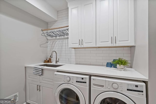 laundry area featuring cabinet space, visible vents, a sink, and washing machine and clothes dryer