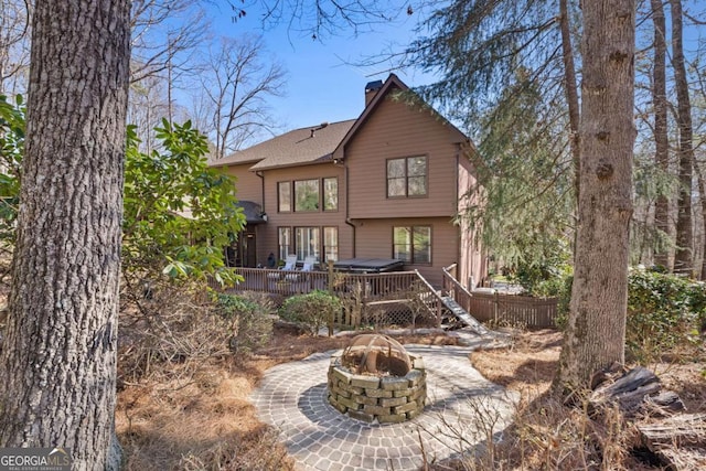 rear view of property featuring a fire pit, a chimney, roof with shingles, fence, and a deck