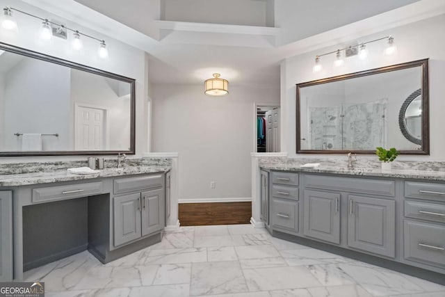 full bathroom with baseboards, a sink, marble finish floor, a shower stall, and two vanities